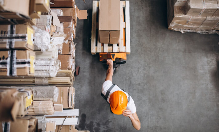 Warehouse worker transporting inventory on pallets in a modern storage facility